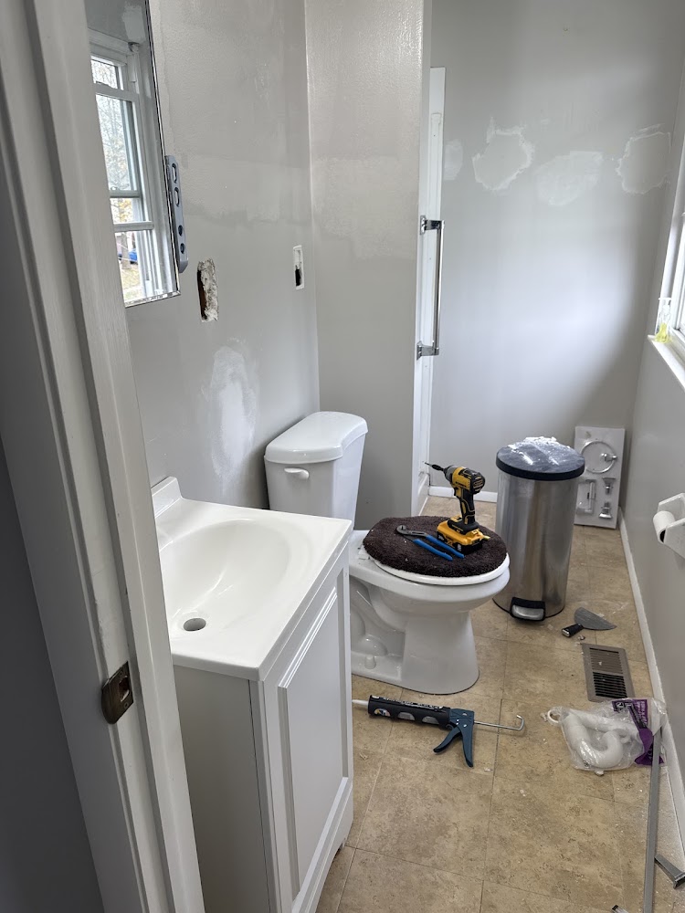 A bathroom remodel in progress, with a new vanity, toilet, and tools mid-installation